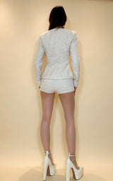 Person wearing a light gray outfit with white shoes against a beige background