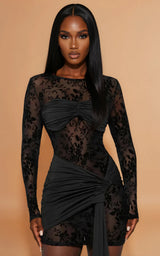 Woman wearing a black lace dress against a beige background