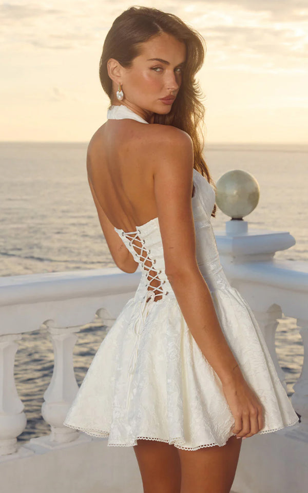 Woman wearing a white lace dress with a scenic background