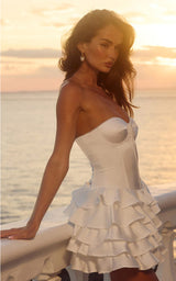 Woman in a white dress standing by the ocean at sunset