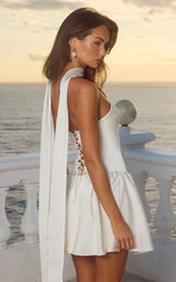 Woman in a ivory corset lace up dress standing by the sea at sunset