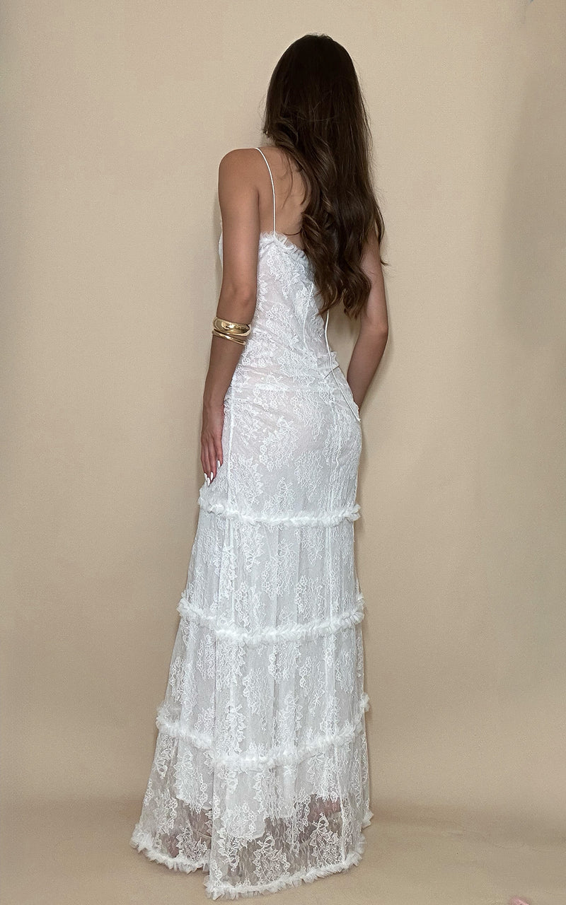 Woman wearing a white lace dress against a beige background