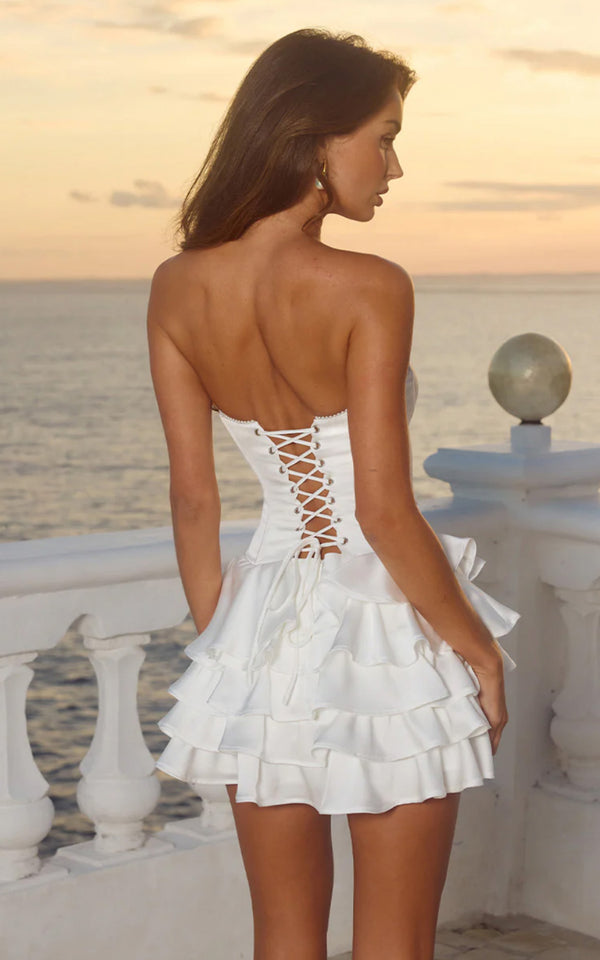 Woman in a white dress standing on a balcony with a scenic background
